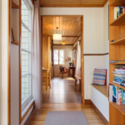 Mandala Bruny Island Hallway View: A perspective looking over office corner, a bright hallway with polished wood floors and a bookshelf on the right.