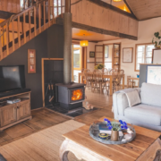 Fireplace & Stairs: A view of the living room featuring a wood heater and a timber staircase leading to a loft bedroom.