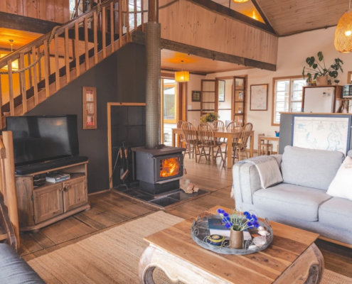 Fireplace & Stairs: A view of the living room featuring a wood heater and a timber staircase leading to a loft bedroom.