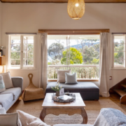 Sunlit Sitting Area: A bright space of the living room with large windows and a view of the water and surrounding trees.