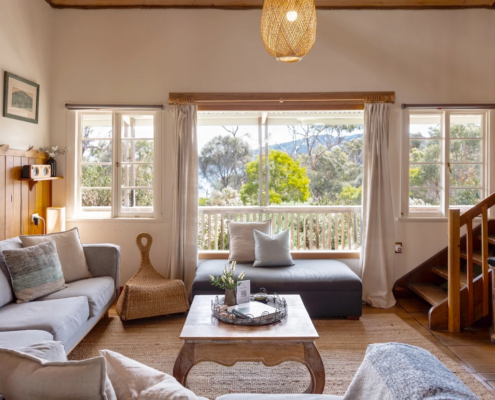 Sunlit Sitting Area: A bright space of the living room with large windows and a view of the water and surrounding trees.