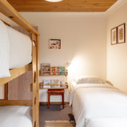 Bunk Room (Bedroom 3): A bright view of the bunk room featuring two single beds and a timber bunk bed set, sleeps 4