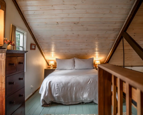 Charming loft bedroom layout featuring a double bed and single bed tucked under wooden beams.